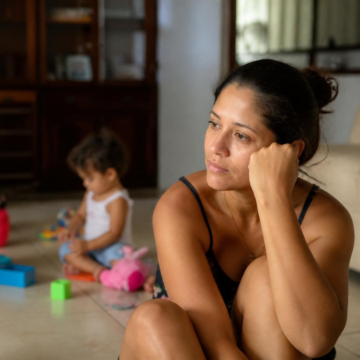 Mãe pensativa observando o filho brincar